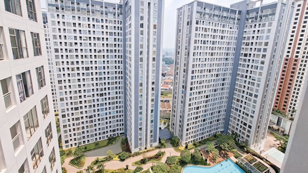 Un immeuble résidentiel de grande hauteur doté de nombreux balcons, d’une piscine et de jardins aménagés.