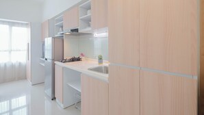 A modern kitchen with light wood cabinets, a stainless steel sink, and a built-in oven. - Basic Studio Apartment At Springlake Summarecon Bekasi (Bekasi)