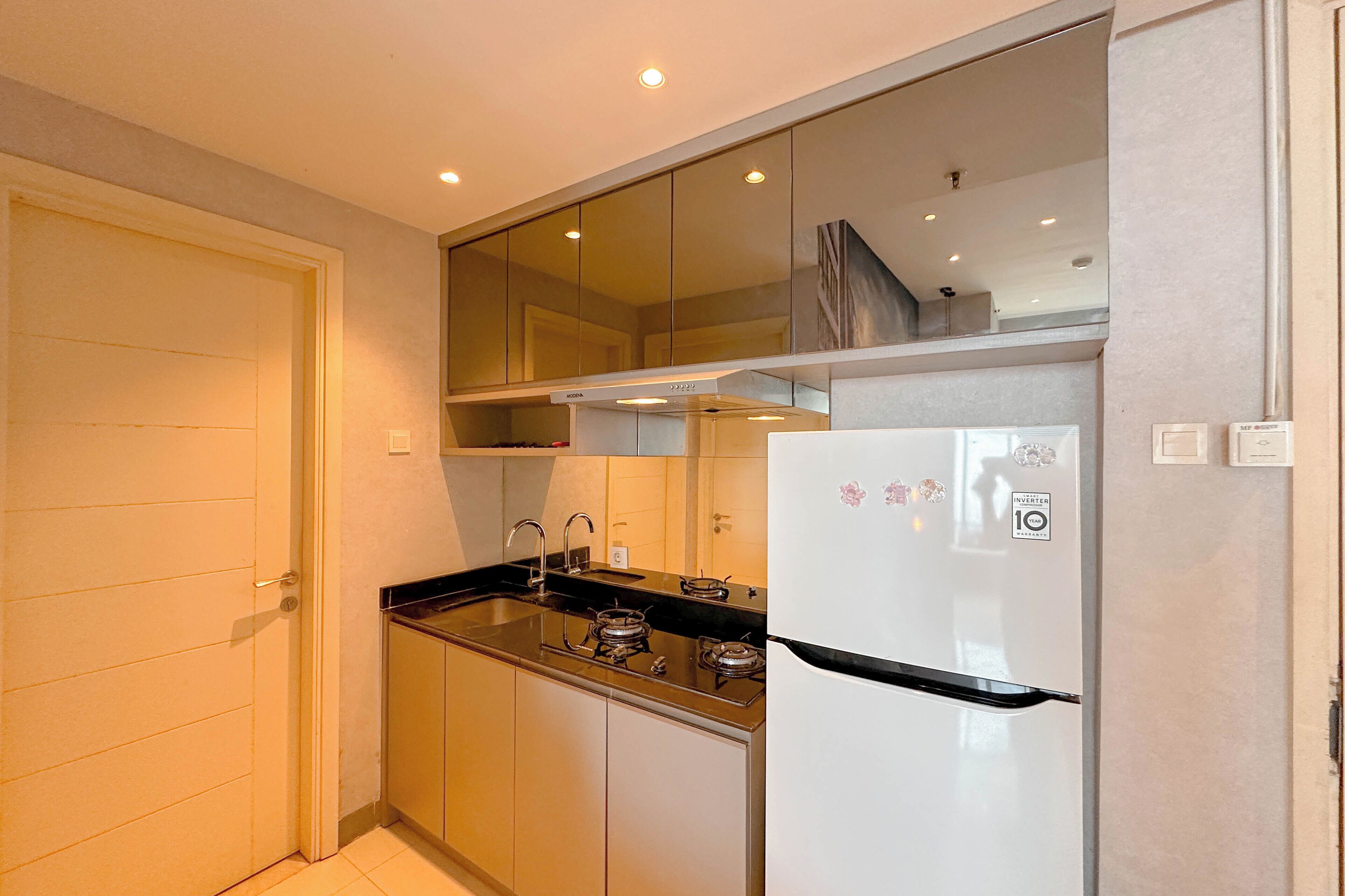 A compact kitchen with a white refrigerator, a stove, and a sink.