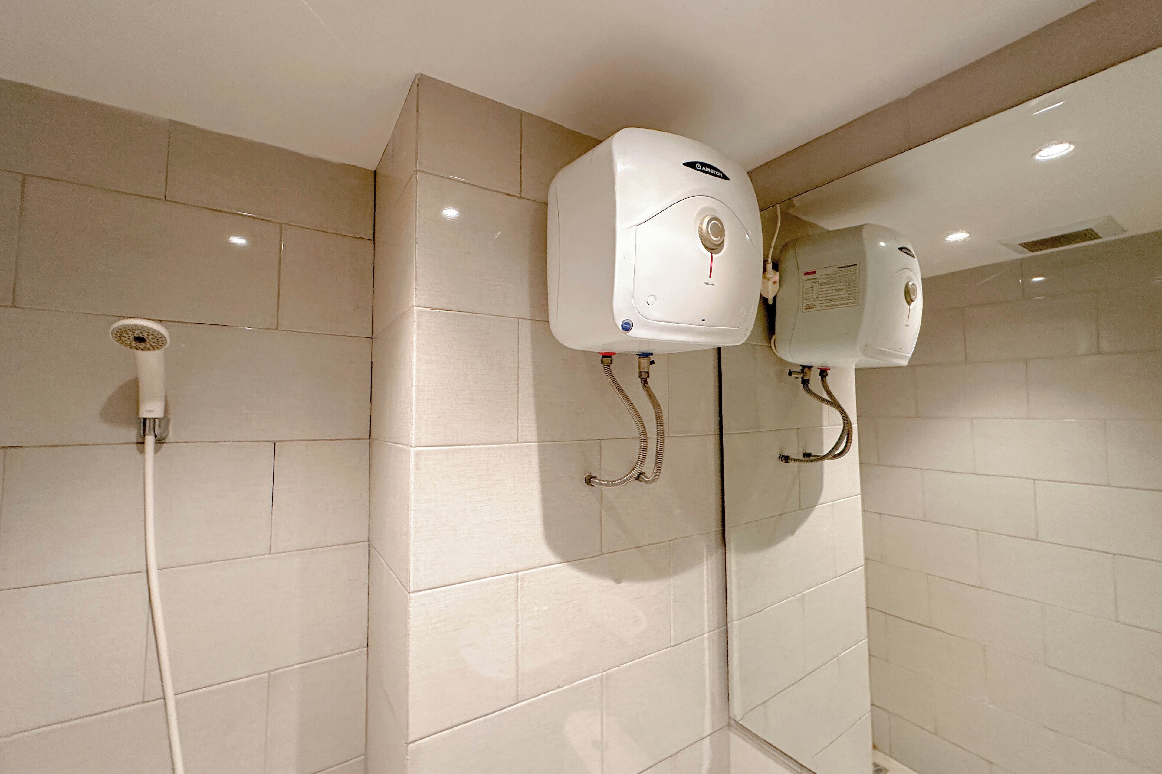 Ein Badezimmer mit zwei Wand-Warmwasserbereitern, einem Händetrockner und einem Handtuchhalter.