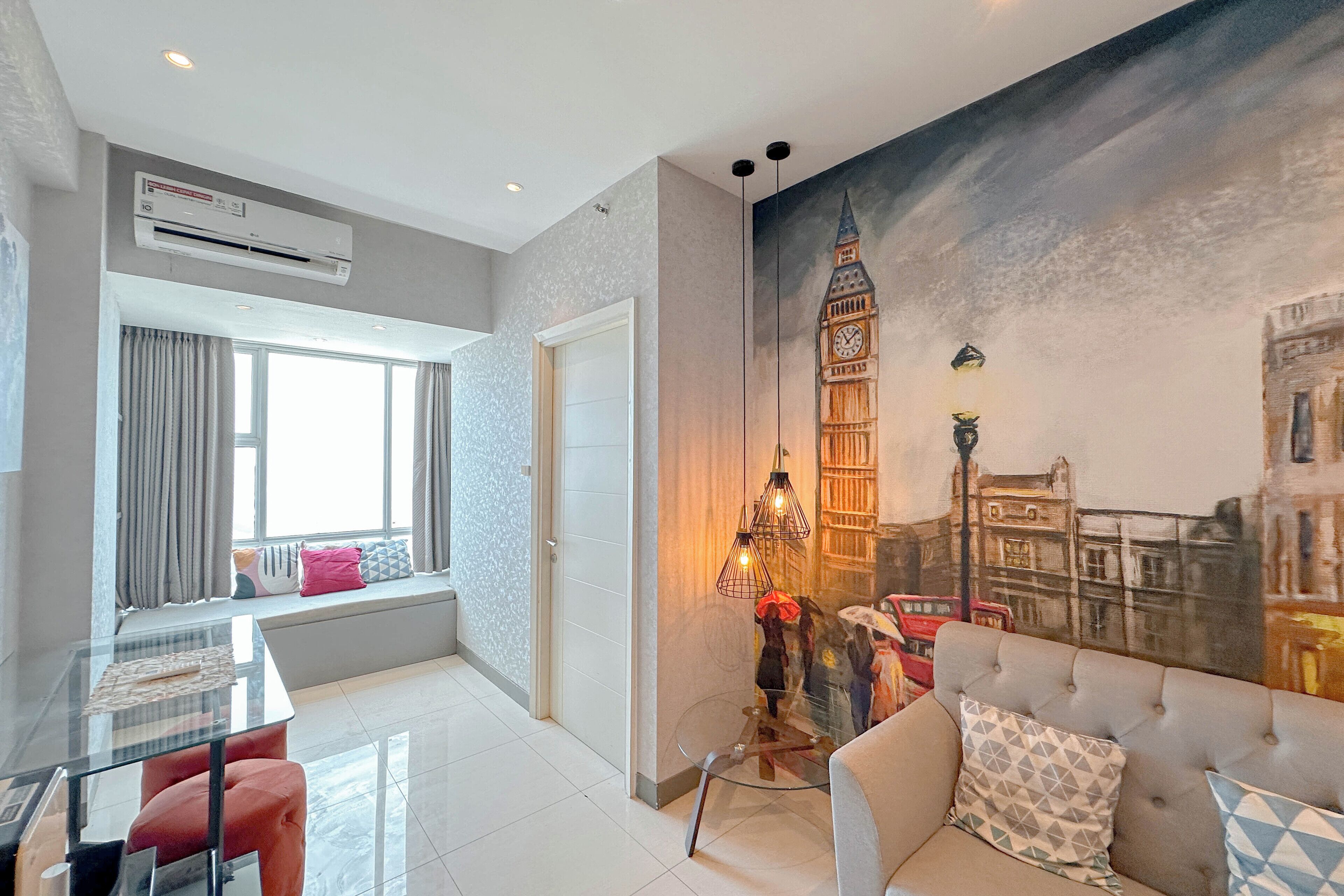 A modern living room with a glass table, a sofa, and a mural of a clock tower.