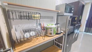 Una cucina con forno a microonde, frigorifero e scolapiatti con utensili.