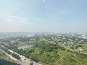 An aerial view of a cityscape with a mix of residential and commercial buildings, a large body of water, and a prominent bridge structure. - Spacious Warm 2Br At Apartment Meikarta (Cikarang)