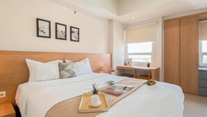 A modern hotel room with a large bed, a desk, and a window with a view. - 1Br Apartment Near President University At Mustika Golf Residence (Cikarang)
