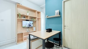 Moderni huone, jossa on seinälle asennettu televisio, pöytä ja kaksi tuolia sekä ovi.