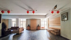 A spacious lobby with a high ceiling, a fireplace, and a seating area with sofas and a table. - Simple Look 2Br Apartment Near Universities At Skyland City Jatinangor (Hegarmanah)