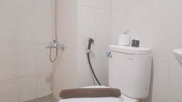 A bathroom with a shower, toilet, and a bidet.