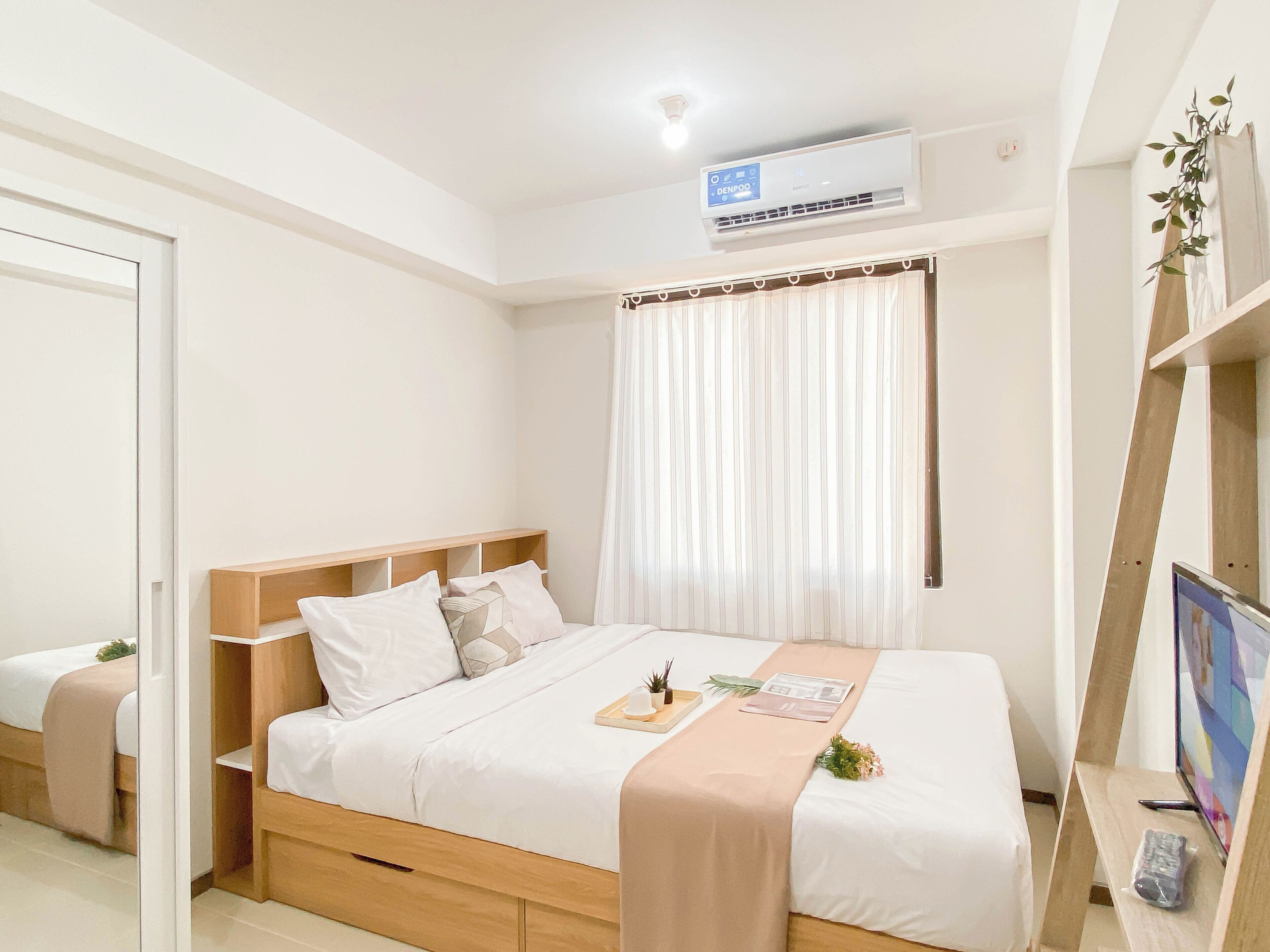 A modern hotel room with a bed, bedside table, air conditioning unit, and a window with curtains.