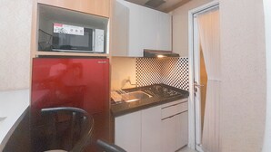 A compact kitchen with a microwave, stove, and sink. - 2Br Near Unpar At Parahyangan Residence Apartment (Bandung)