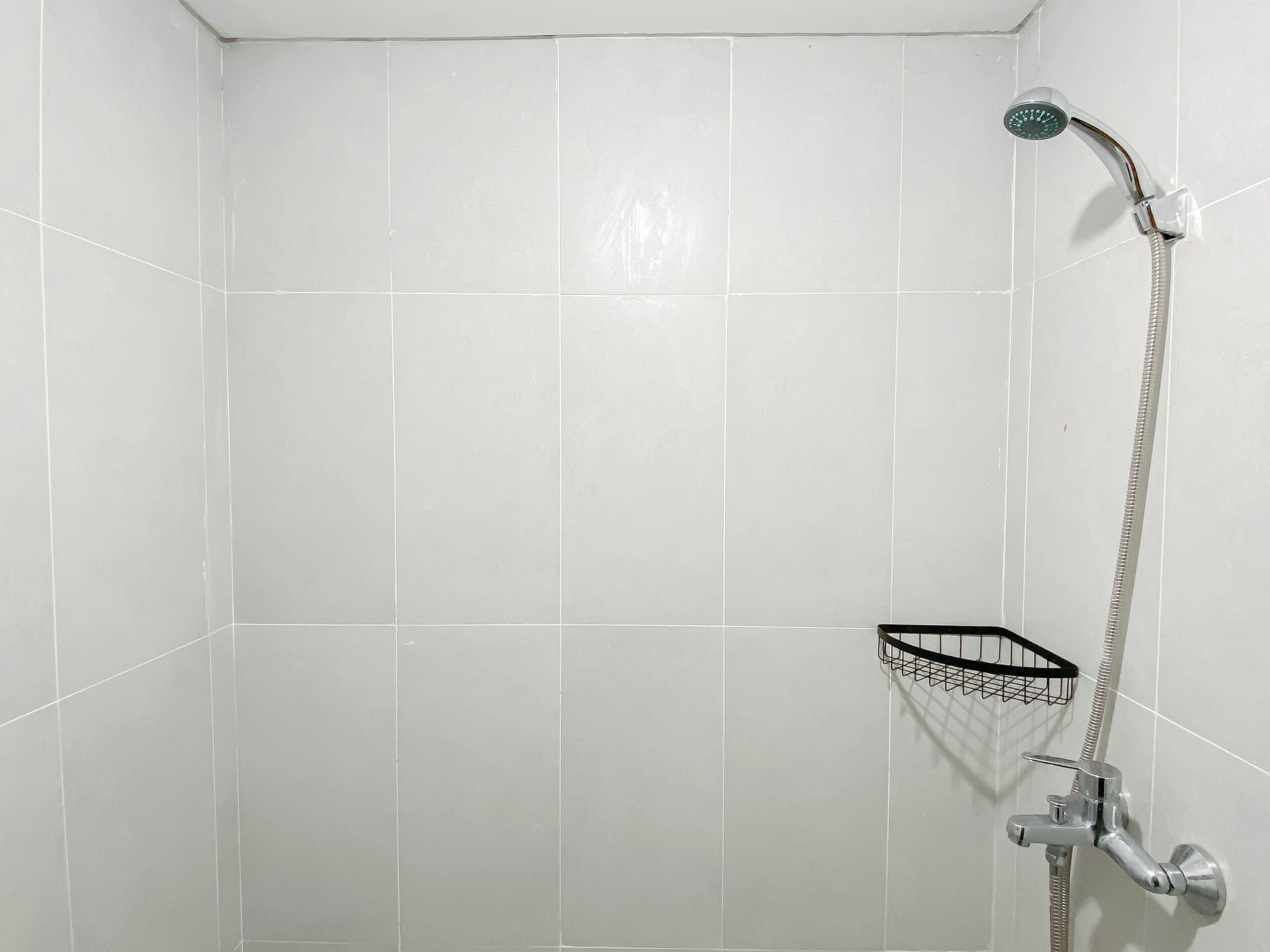 A shower area with white tiles, a showerhead, and a handheld shower attachment.