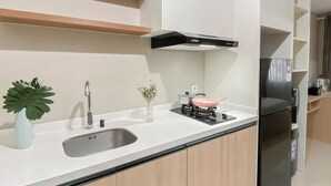 Una cocina moderna con un lavamanos de acero inoxidable, una estufa a gas, un extractor de aire negro y un refrigerador empotrado.