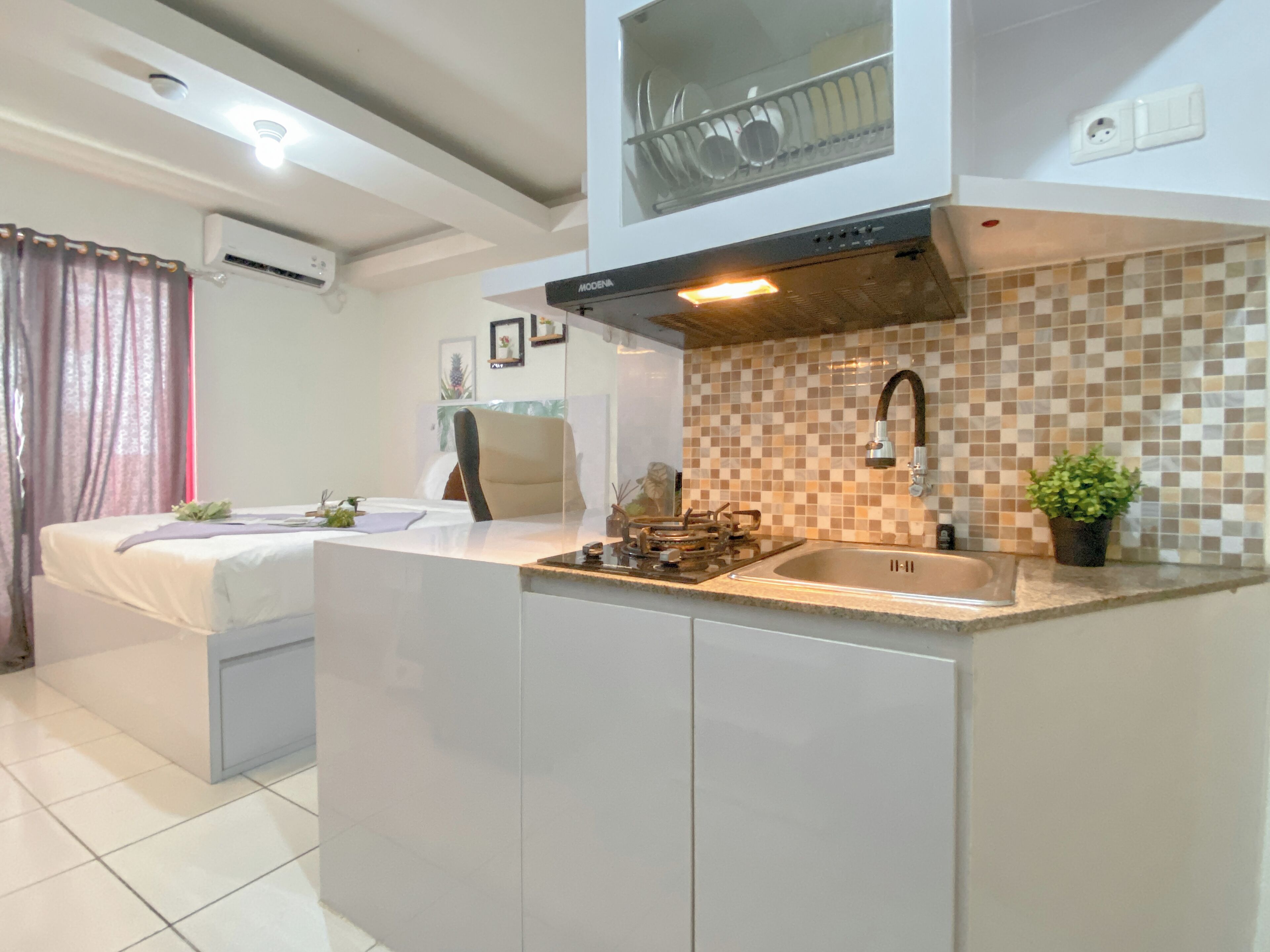 A compact kitchen with a built-in stove, a sink, and a dish rack above the counter.
