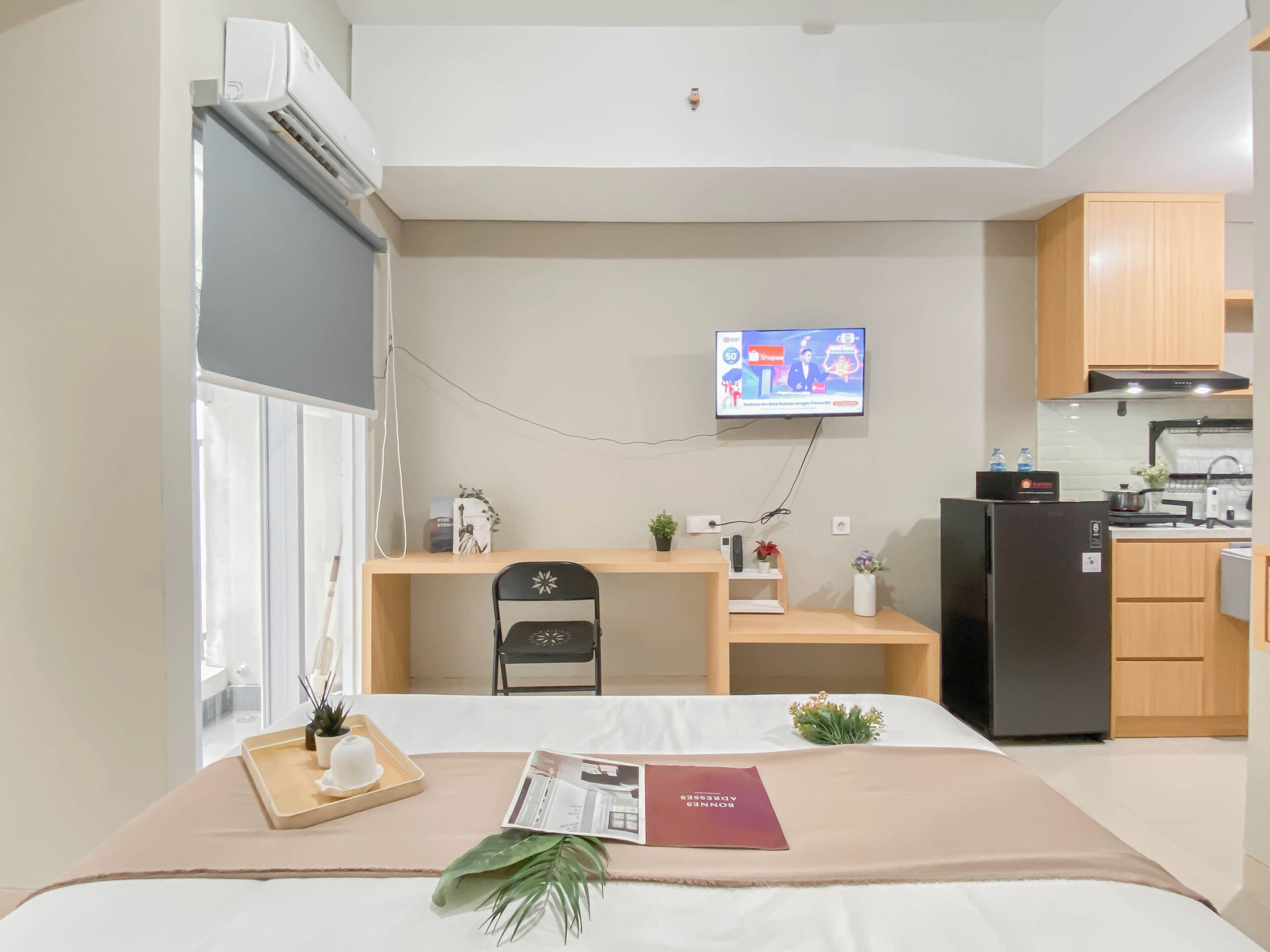 Ein modernes Hotelzimmer mit Bett, Schreibtisch, Fernseher und einer Küchenzeile.
