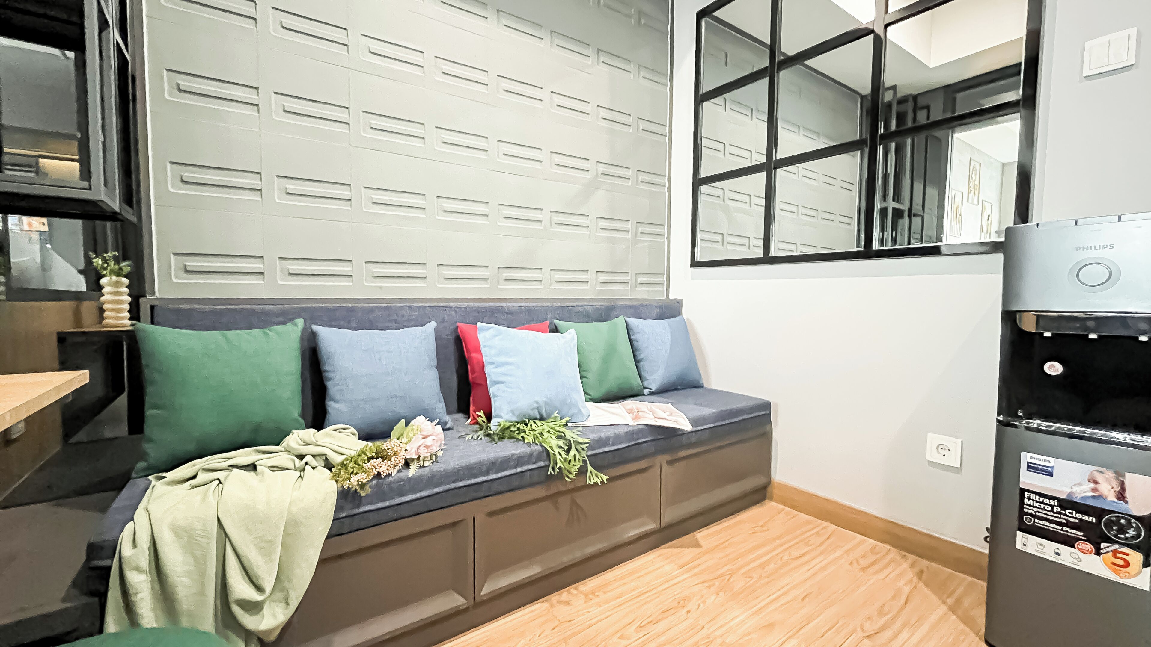 A modern living room with a built-in bench, a large window, and a water dispenser.