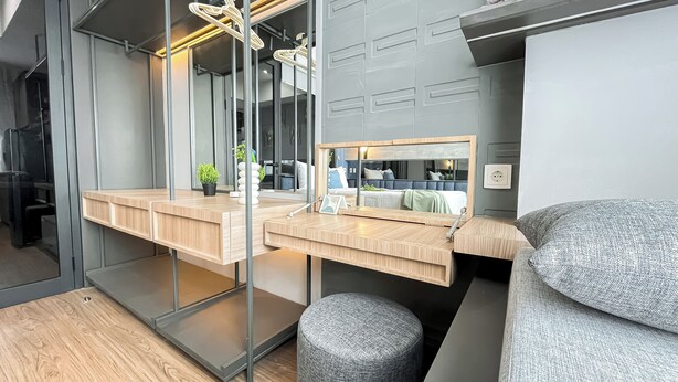 A modern bedroom with a wooden desk, a large mirror, and a grey upholstered bench. - 1Br Near Aeon Alam Sutera At Collins Boulevard Apartment (Tangerang)