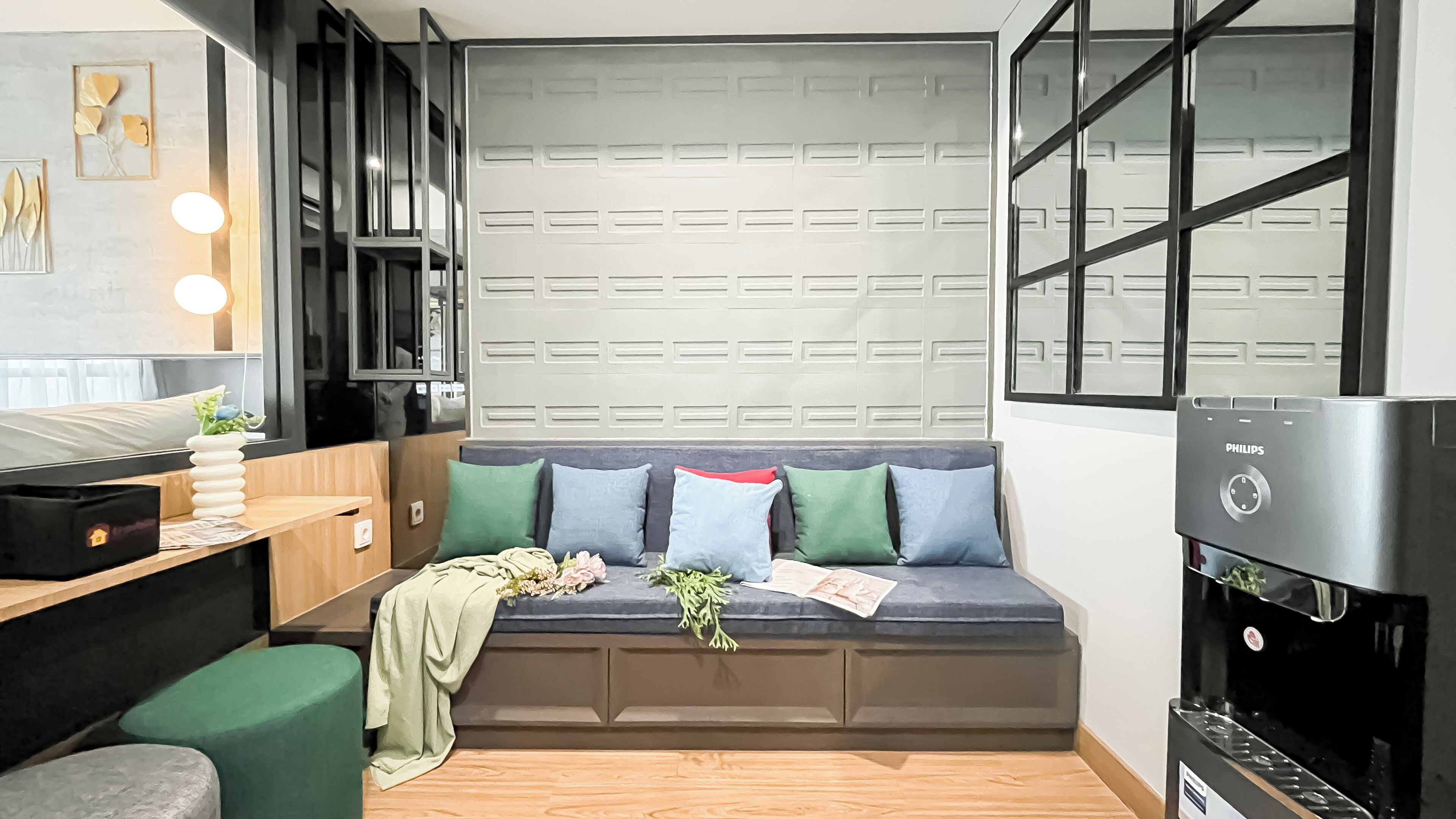 A modern, compact living space with a built-in bench, a small table, and a water dispenser.