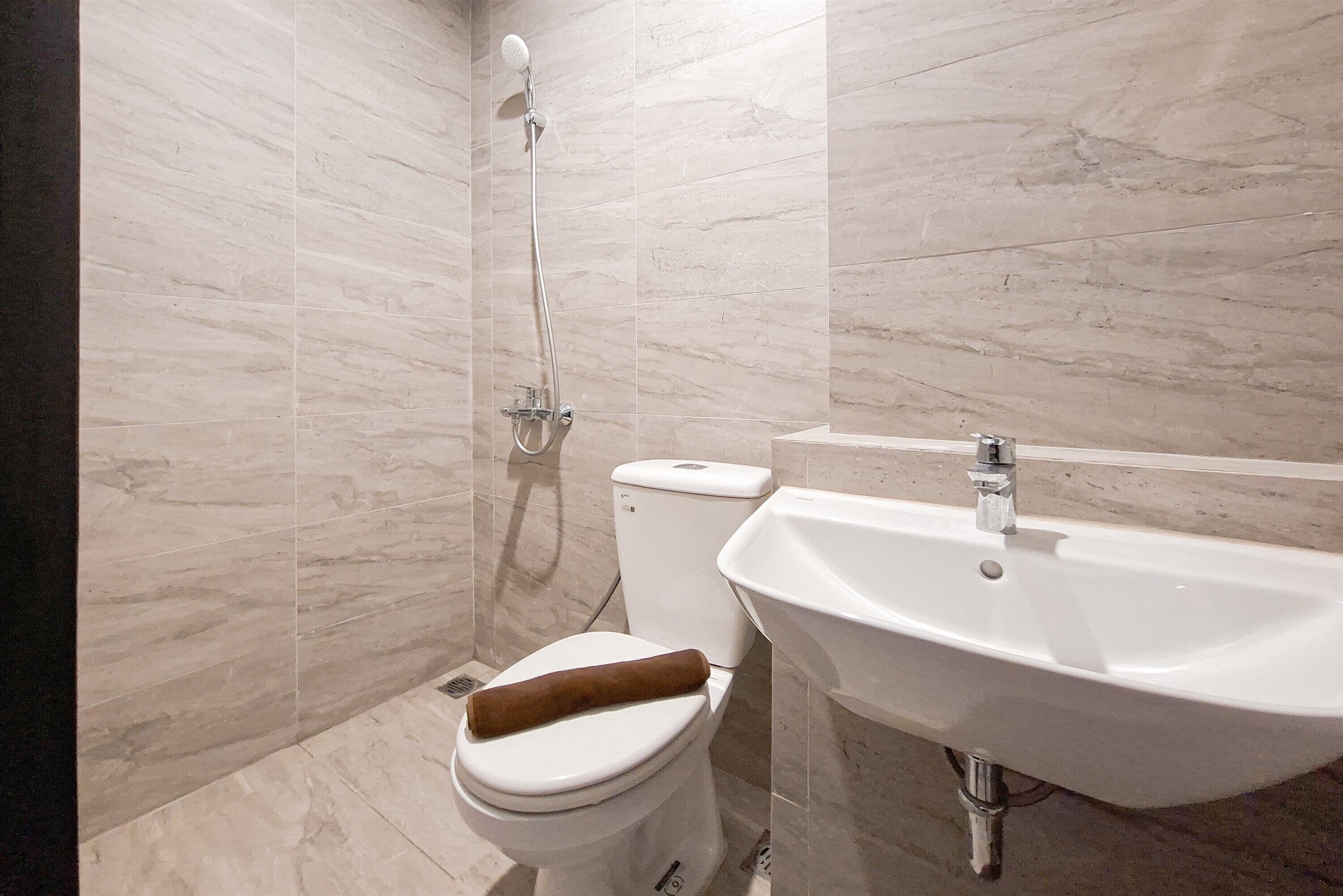 A bathroom with a toilet, a shower, and a sink.