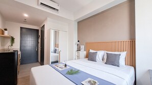 A modern hotel room with a large bed, a wooden headboard, a desk, and a mirror. - Modern Studio Near Binus Alam Sutera At Collins Boulevard Apartment (Tangerang)