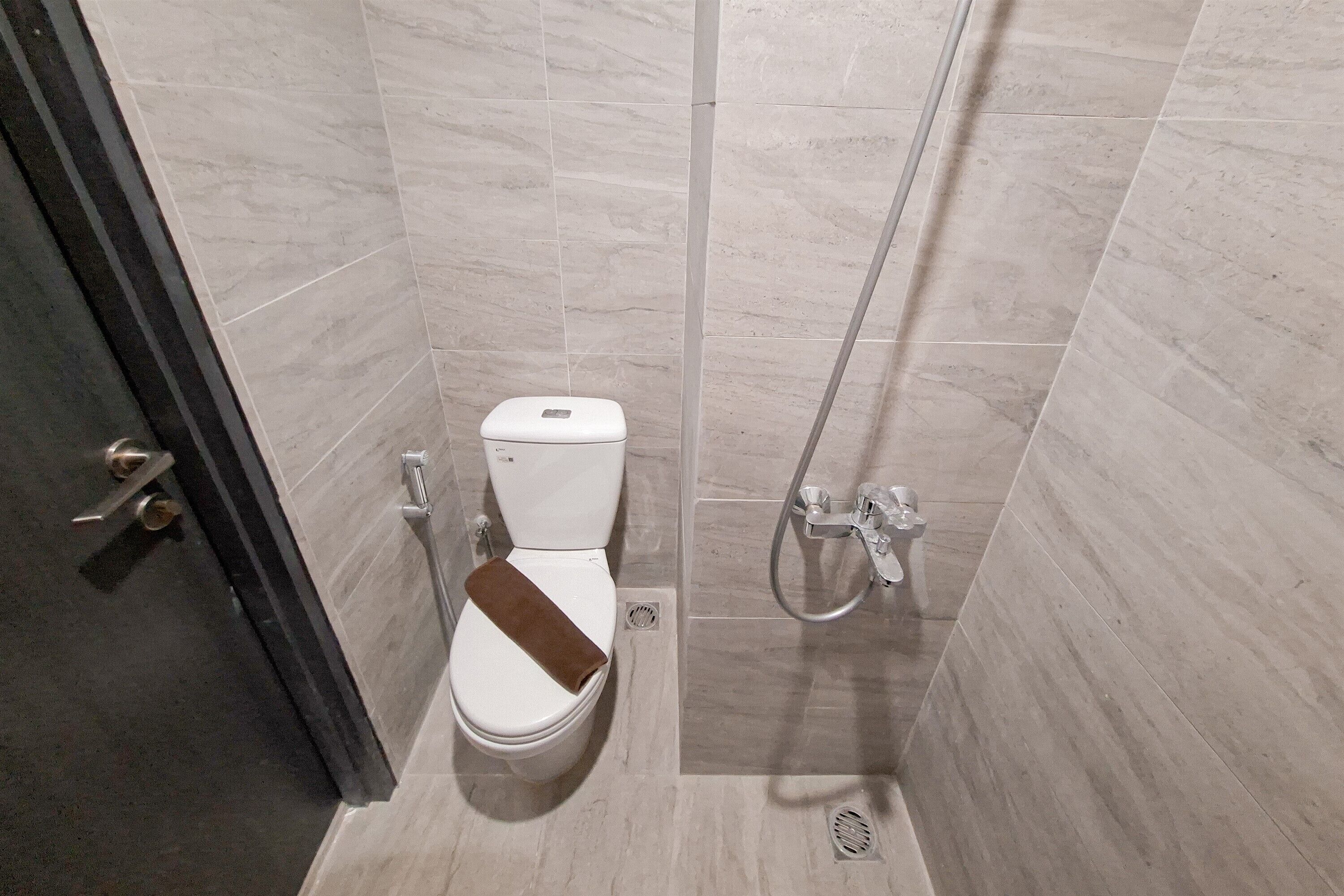 A small, modern bathroom with a toilet, shower, and a towel rack.