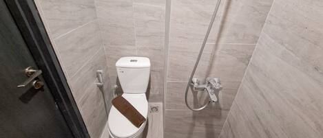 A small, modern bathroom with a toilet, shower, and a towel rack.