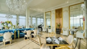 A spacious dining area with a blue sofa, white chairs, and a piano. - Minimalist Look Studio Apartment At Art Deco (Bandung)