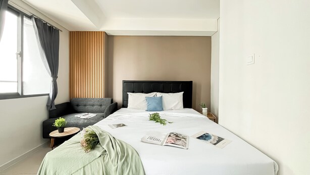 A hotel room with a bed, a sofa, a small table, and a window with curtains. - Studio Near Kalideres Station At Daan Mogot City Apartment (Jakarta)