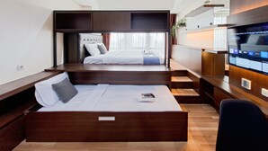 A modern hotel room with a bed, a sofa bed, a TV, and a desk. - Stylish Studio Apartment At The Smith Alam Sutera (Tangerang)