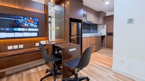 A modern kitchen with wooden cabinets, a black refrigerator, and a built-in TV displaying various apps. - Stylish Studio Apartment At The Smith Alam Sutera (Tangerang)