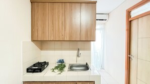 Une cuisine avec des meubles en bois, une cuisinière à gaz, un évier et une petite plante.