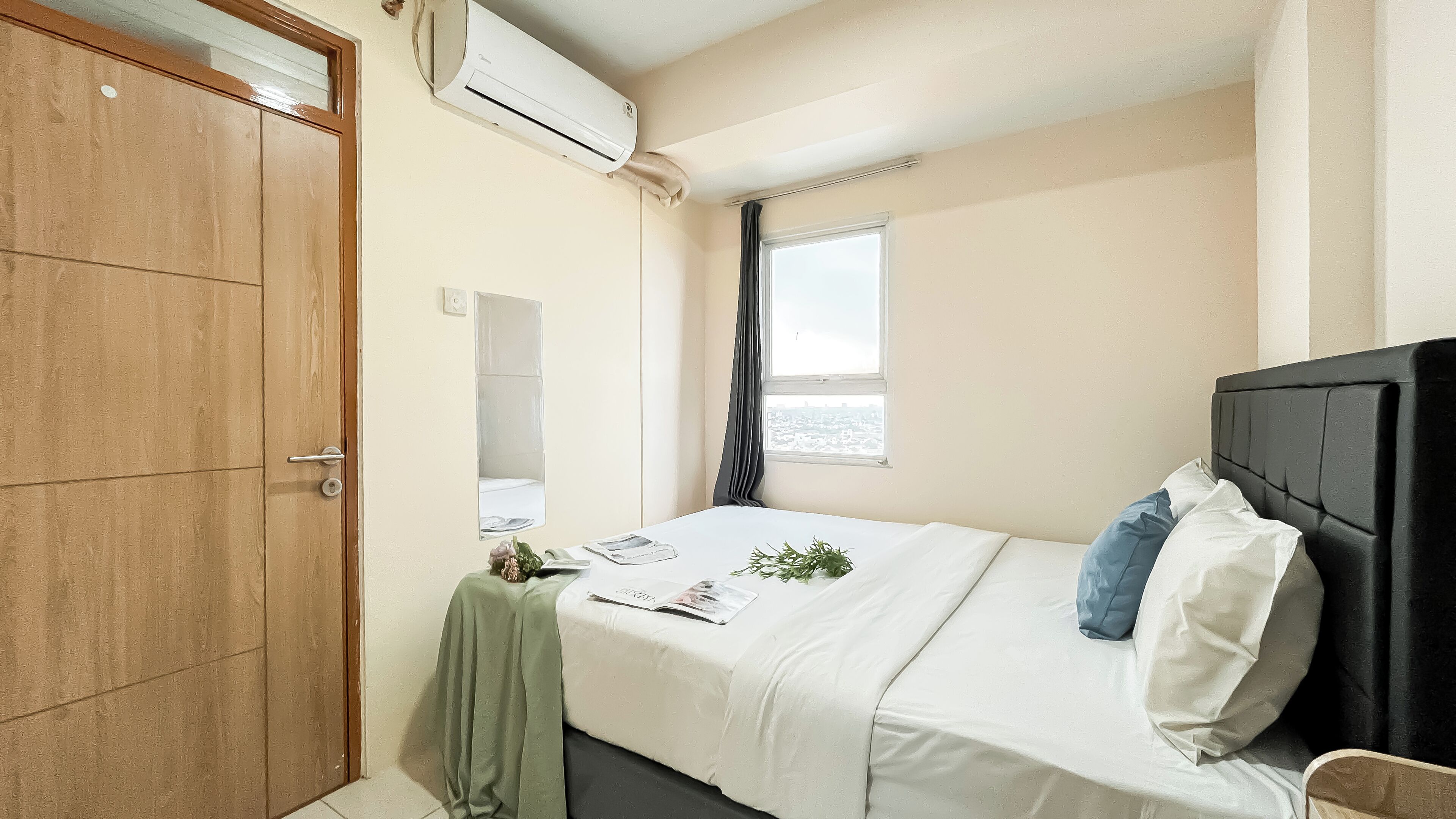 Un dormitorio con cama, ventana con cortinas, armario de madera y aire acondicionado.