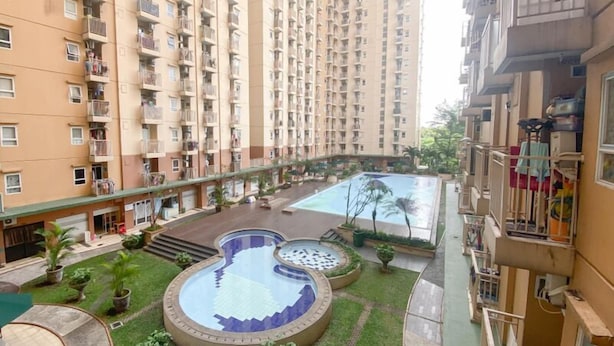 Un immeuble résidentiel doté de nombreux balcons, d’une cour intérieure avec une piscine et d’un petit jardin.