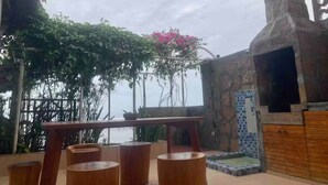 An outdoor seating area with a table and chairs, surrounded by greenery and a stone wall.