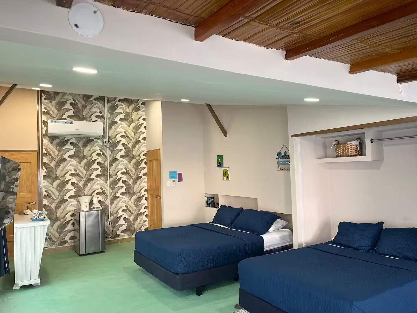 Une chambre avec deux lits, une petite kitchenette et un ventilateur de plafond.