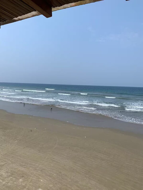 A beach with waves and a clear sky.
