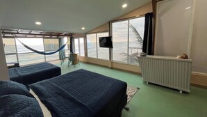 A room with two beds, a TV, and a view of the ocean.