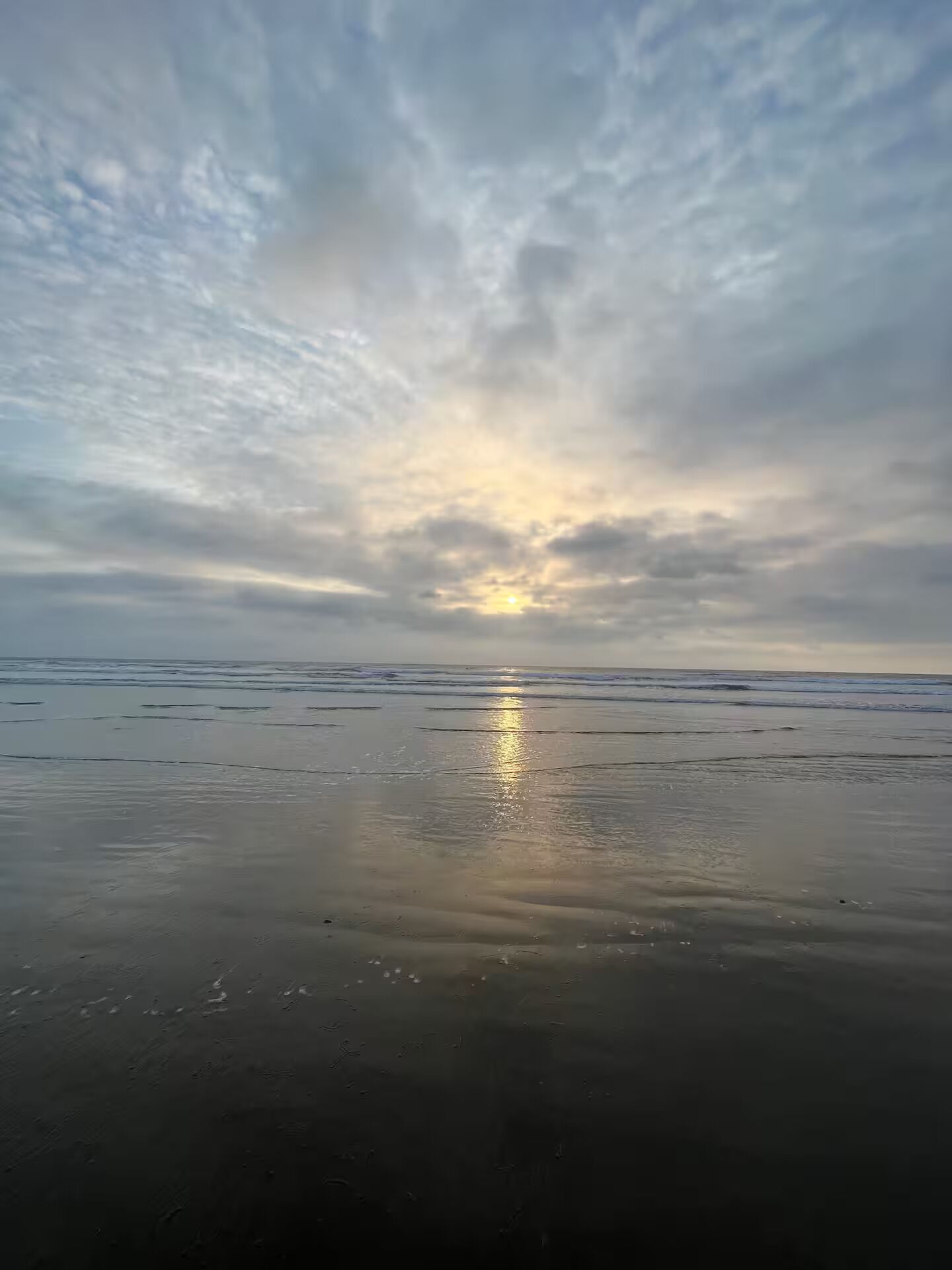 A beach with a calm sea and a cloudy sky.