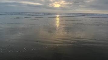 A beach with a calm sea and a cloudy sky.
