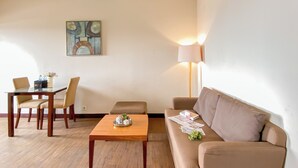 Una sala de estar con una mesa de centro de madera, sofá color beige y un comedor con sillas y una mesa.