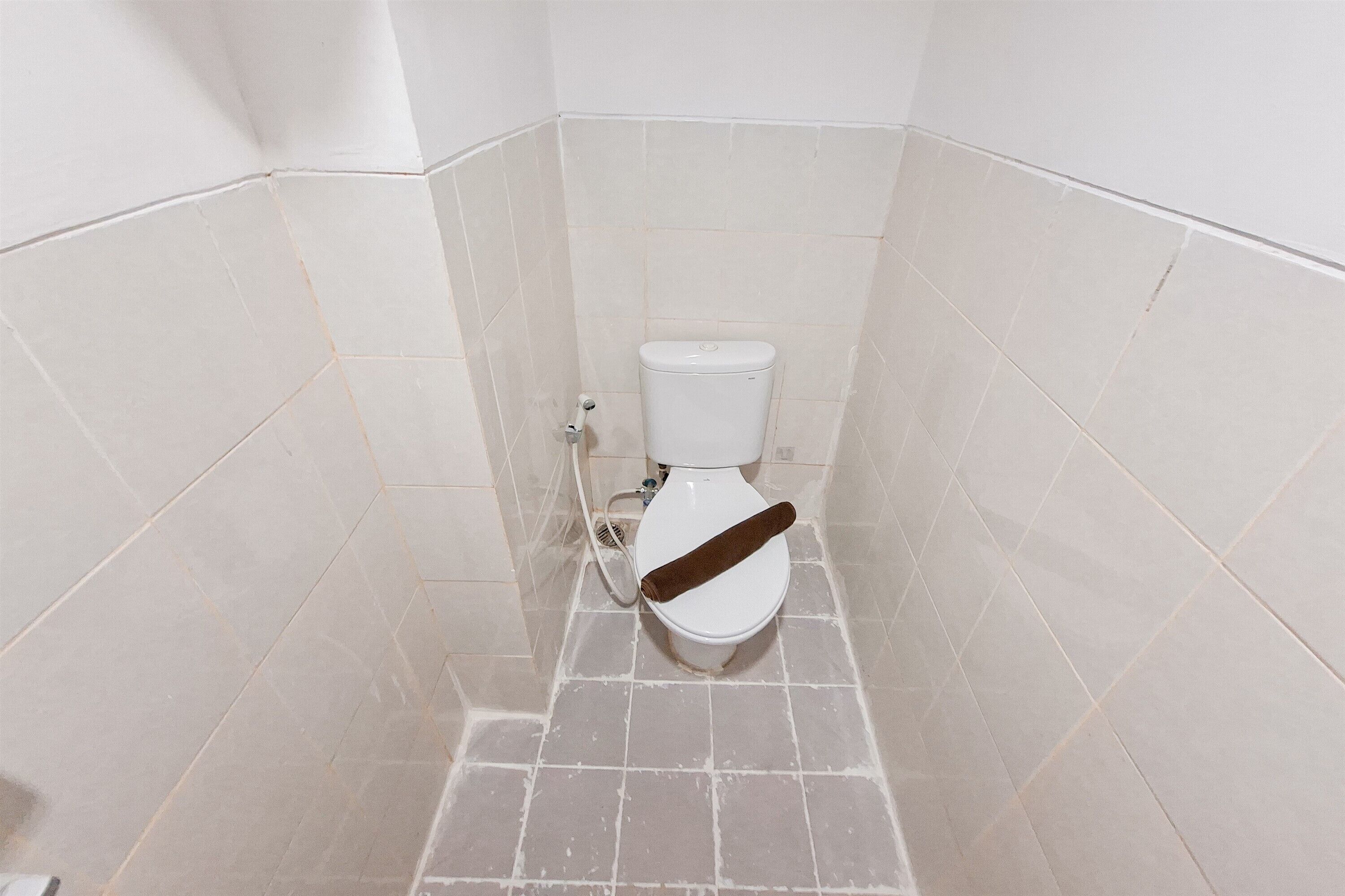 Un baño pequeño con azulejos, un inodoro y una tubería visible.