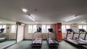 Ein Fitnessstudio mit Laufbändern, einer Ziegelstütze und großen Fenstern.