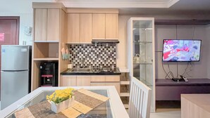 Una cucina moderna con mobili in legno, zoccolo piastrellato, piano cottura integrato e frigorifero.