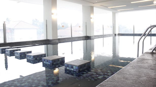 Piscina interna con acqua limpida, gradini piastrellati e vista sugli edifici esterni.