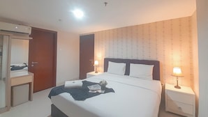 Una camera d'hotel con un letto, comodini, una lampada, uno specchio e un condizionatore d'aria.