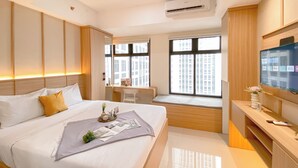 A modern hotel room with a large bed, a desk, a TV, and a window with a city view.