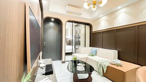 A modern hotel room with a sofa, a coffee table, and a TV. - Stylish And Modern 2Br At Apartment Collins Boulevard (Tangerang)
