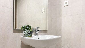 A bathroom with a white sink, a mirror, and a potted plant. - Studio With Direct Access Mall At Pollux Chadstone Apartment (Cikarang)