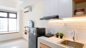 A modern kitchen with a black refrigerator, stainless steel sink, and a window with blinds. - Studio With Direct Access Mall At Pollux Chadstone Apartment (Cikarang)