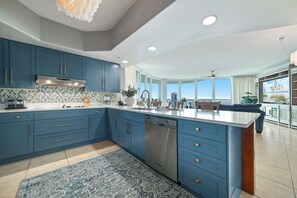 A kitchen with blue cabinets, a dishwasher, and a large island.