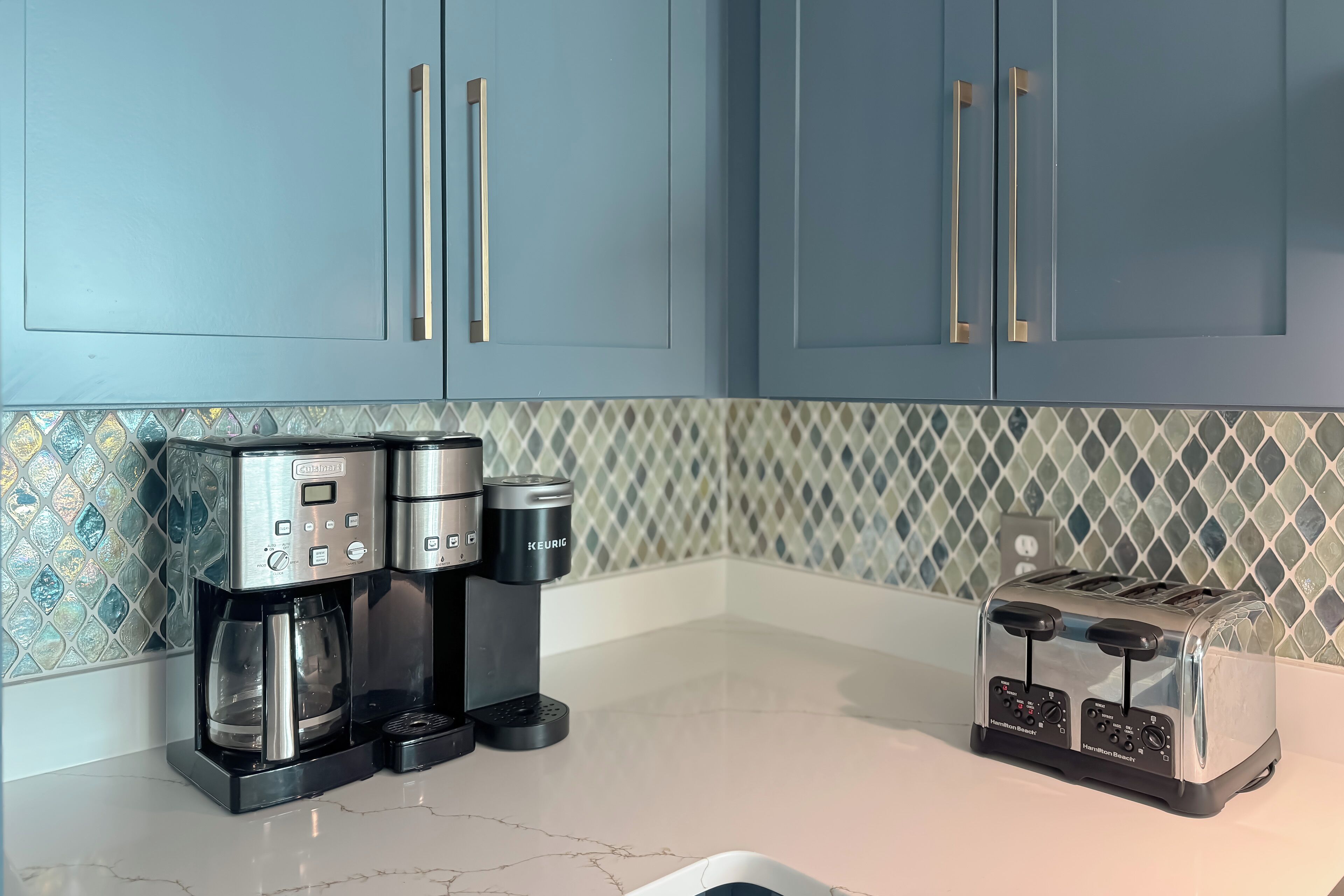A kitchen with a coffee maker, toaster, and blue cabinets.