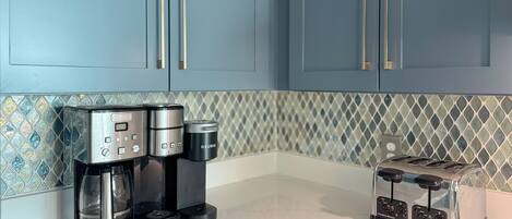 A kitchen with a coffee maker, toaster, and blue cabinets.